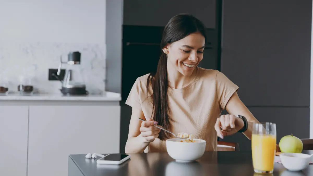  Frau sitzt lächelnd beim Frühstück 