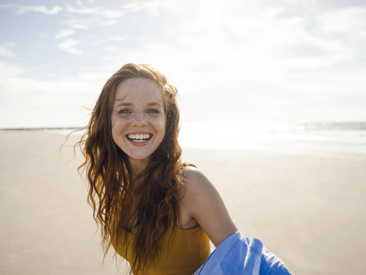  Glückliche Frau am Strand mit Beachwaves Frisur 