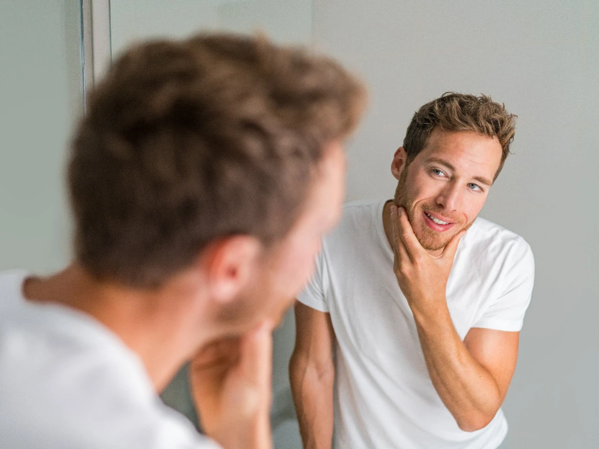  Mann schaut in den Spiegel nach der Rasur 
