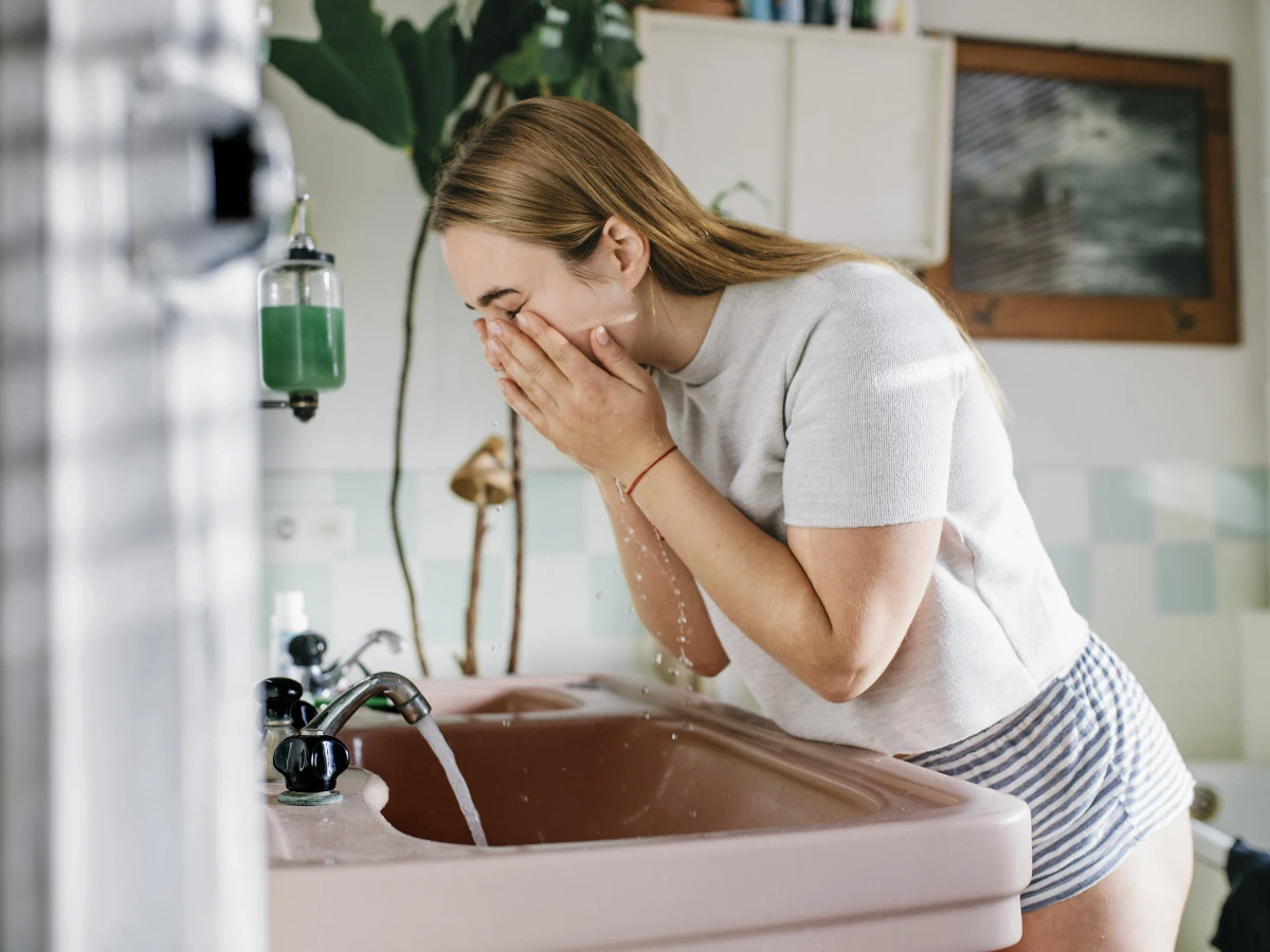  Frau wäscht sich ihr Gesicht im Badezimmer 