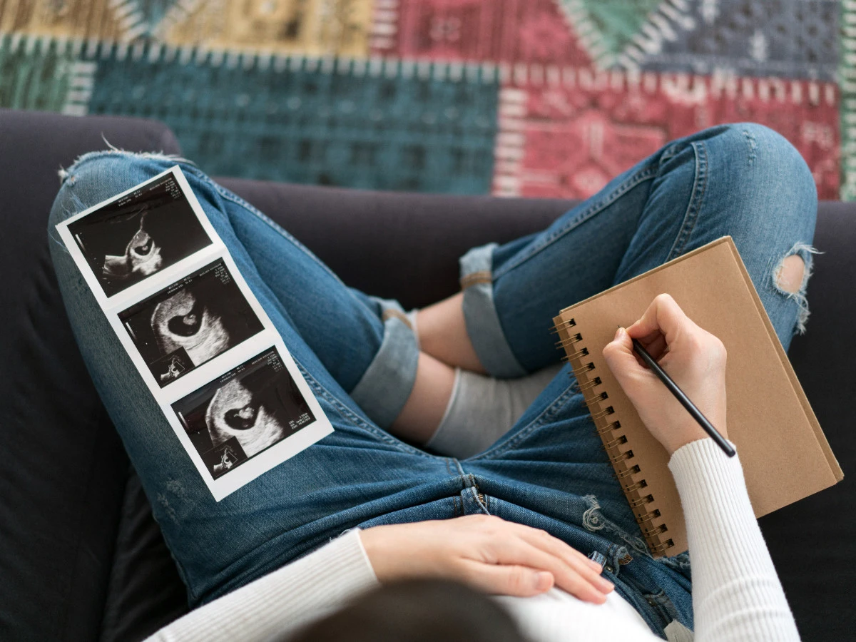  Schwangere Frau mit Ultraschall Bildern von ihrem Baby macht Notizen 
